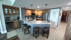 Una cocina moderna con una isla central, taburetes de bar y un comedor.
