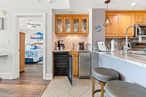 Una cocina moderna con armarios de madera, un enfriador de vino integrado y una zona de bar con taburetes.