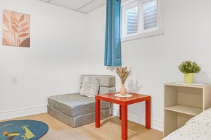 A room with a grey sofa, a red table, a small potted plant, and a blue curtain.