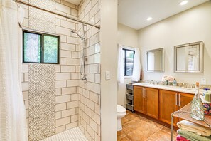 A bathroom with a shower, toilet, and sink area.