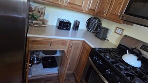 A kitchen with wooden cabinets, a stainless steel refrigerator, a microwave, a stove, and a toaster. - Cozy 2-bedroom house in beautiful Pocahontas with AC (Pocahontas)