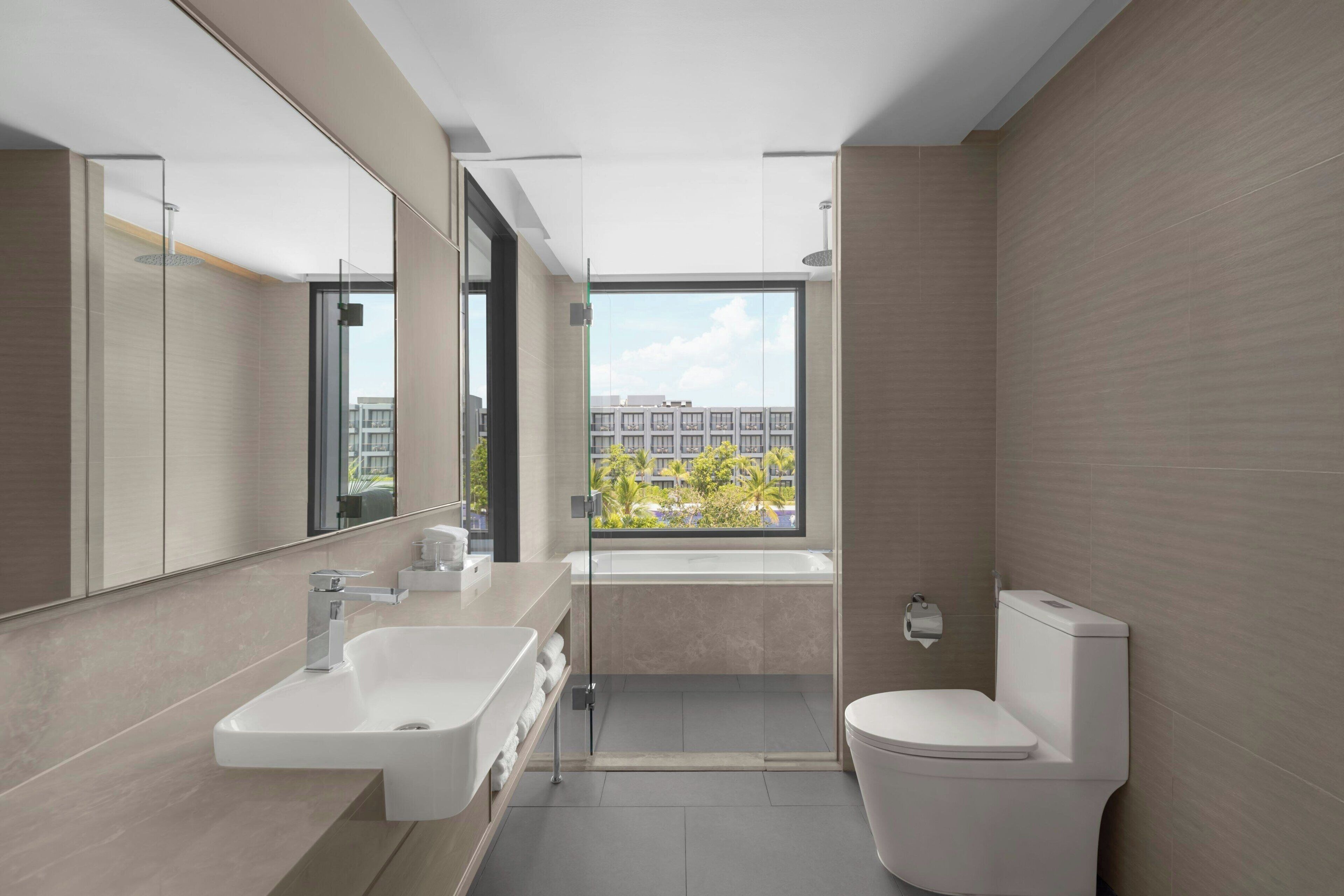 A modern bathroom with a large mirror, a bathtub, a toilet, and a shower.