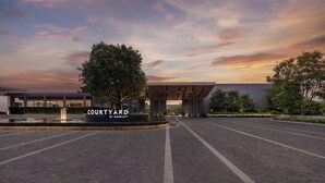 Sisäpiha, jossa on kyltti, jossa lukee ”COURTYARD BY MARRIOTT”, ja jonka ympärillä on puita sekä päällystetty kävelyreitti.