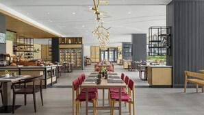 Un restaurante moderno con una larga mesa de comedor, sillas de madera y una lámpara colgante central.