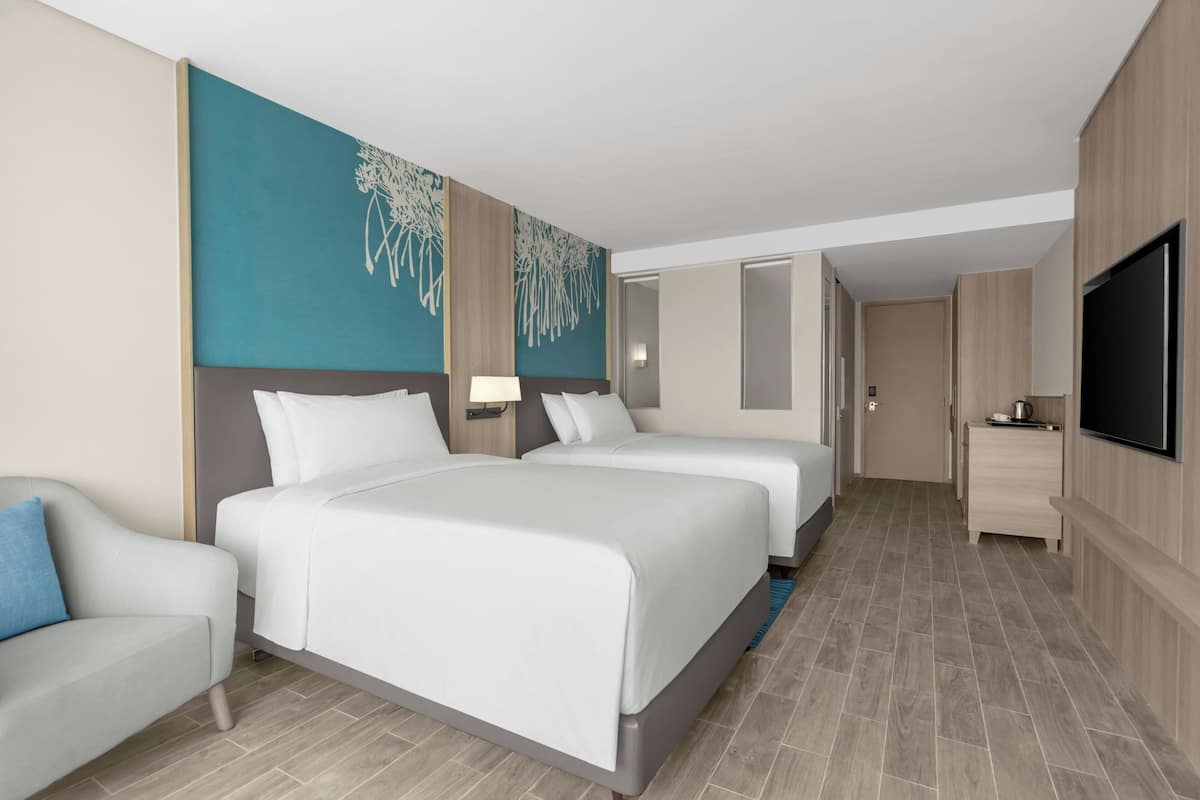 Een hotelkamer met twee bedden, een televisie, een bureau en een stoel.