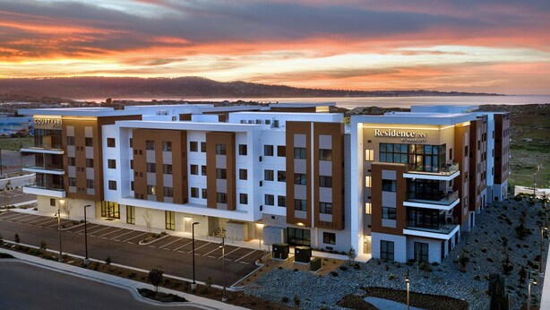 Et moderne hotel med en gårdhave, flere etager og udsigt til solnedgangen.