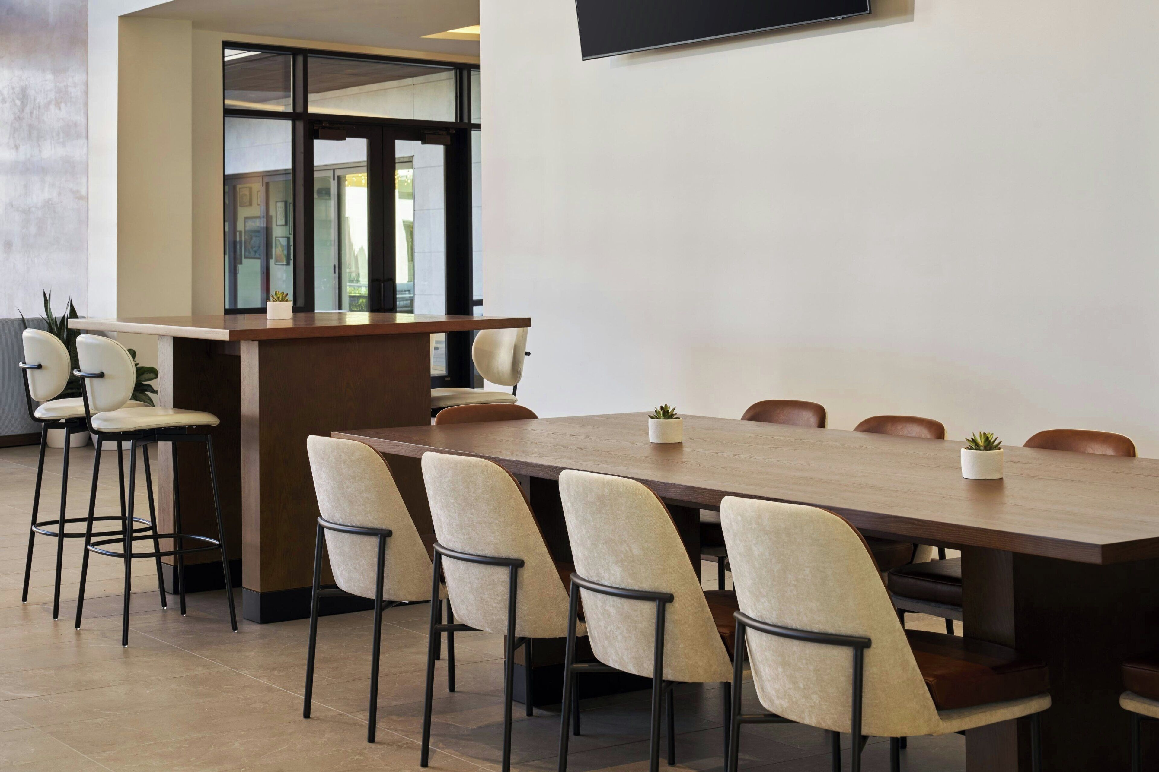 A modern conference room with a long table, six chairs, and a small bar area.