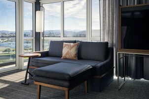 Una habitación moderna con sofá, una mesita auxiliar y un amplio ventanal con vistas a la ciudad.