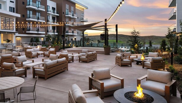 An outdoor patio area with multiple seating arrangements, including sofas and chairs, and a fire pit. - Courtyard By Marriott Sand City Monterey (Seaside)
