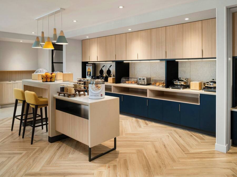 Una cocina moderna con armarios de madera, una isla central, taburetes de bar e iluminación colgante.