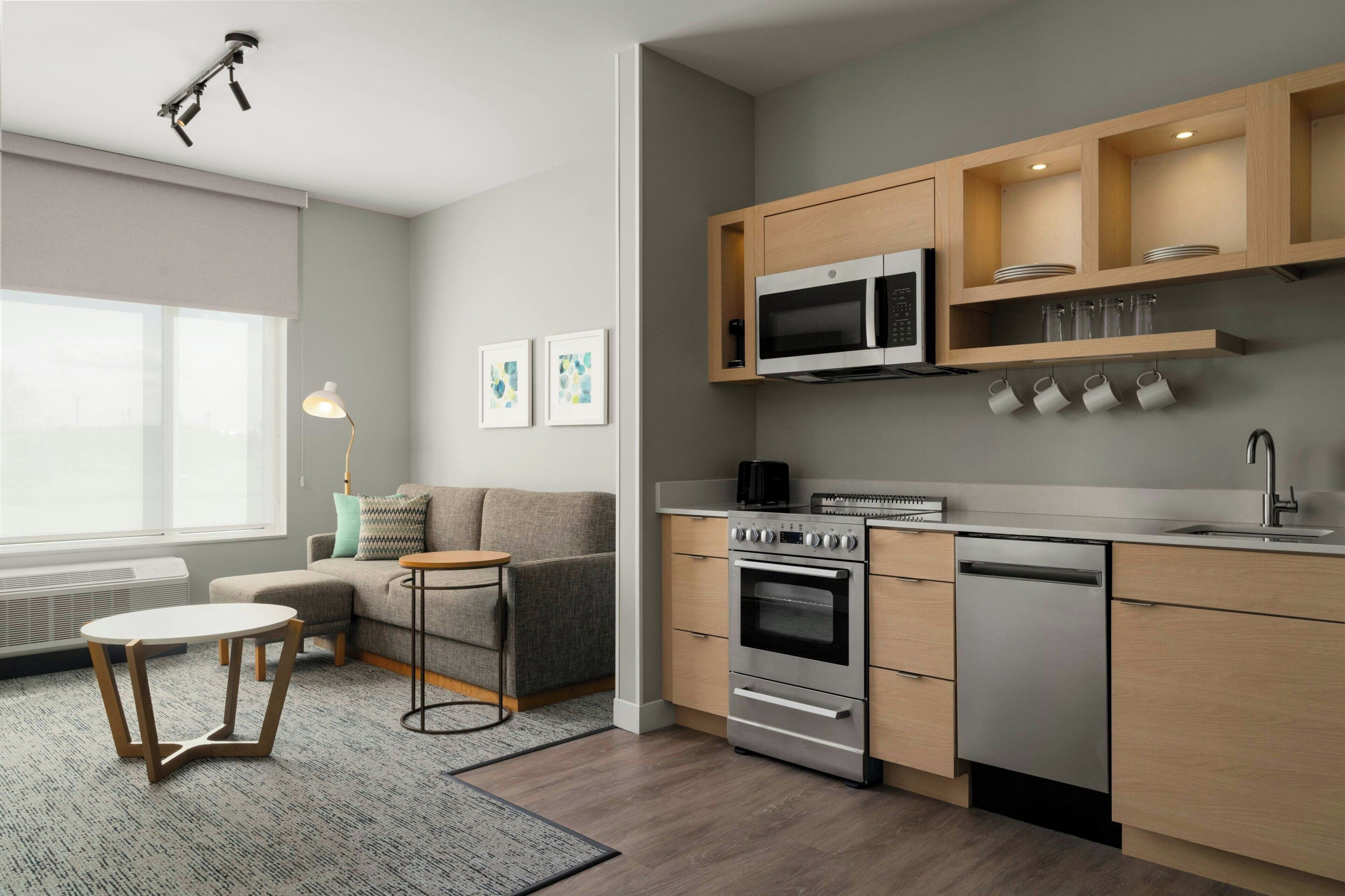 Uma cozinha moderna com eletrodomésticos embutidos, uma sala de jantar com sofá e mesa, e uma janela que proporciona iluminação natural.