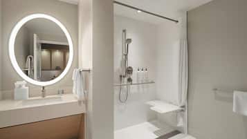 A modern bathroom with a round mirror, a shower, and a vanity with a sink.