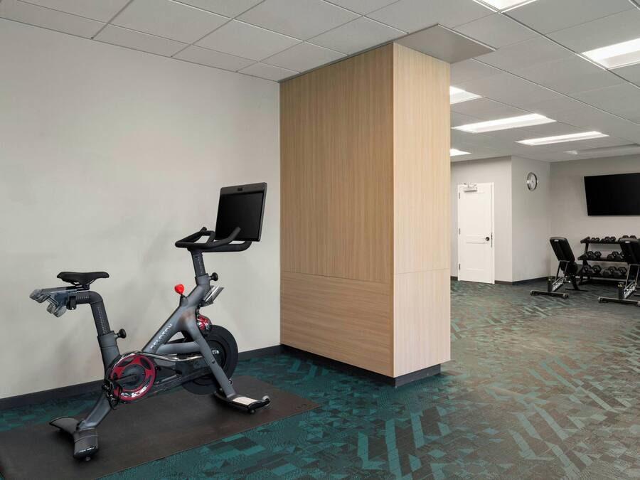 Une salle de remise en forme équipée de vélos d’exercice, d’un téléviseur et d’une horloge murale.