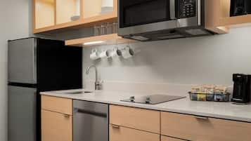 A modern kitchen with a stainless steel refrigerator, a microwave, a sink with a faucet, and a coffee maker.