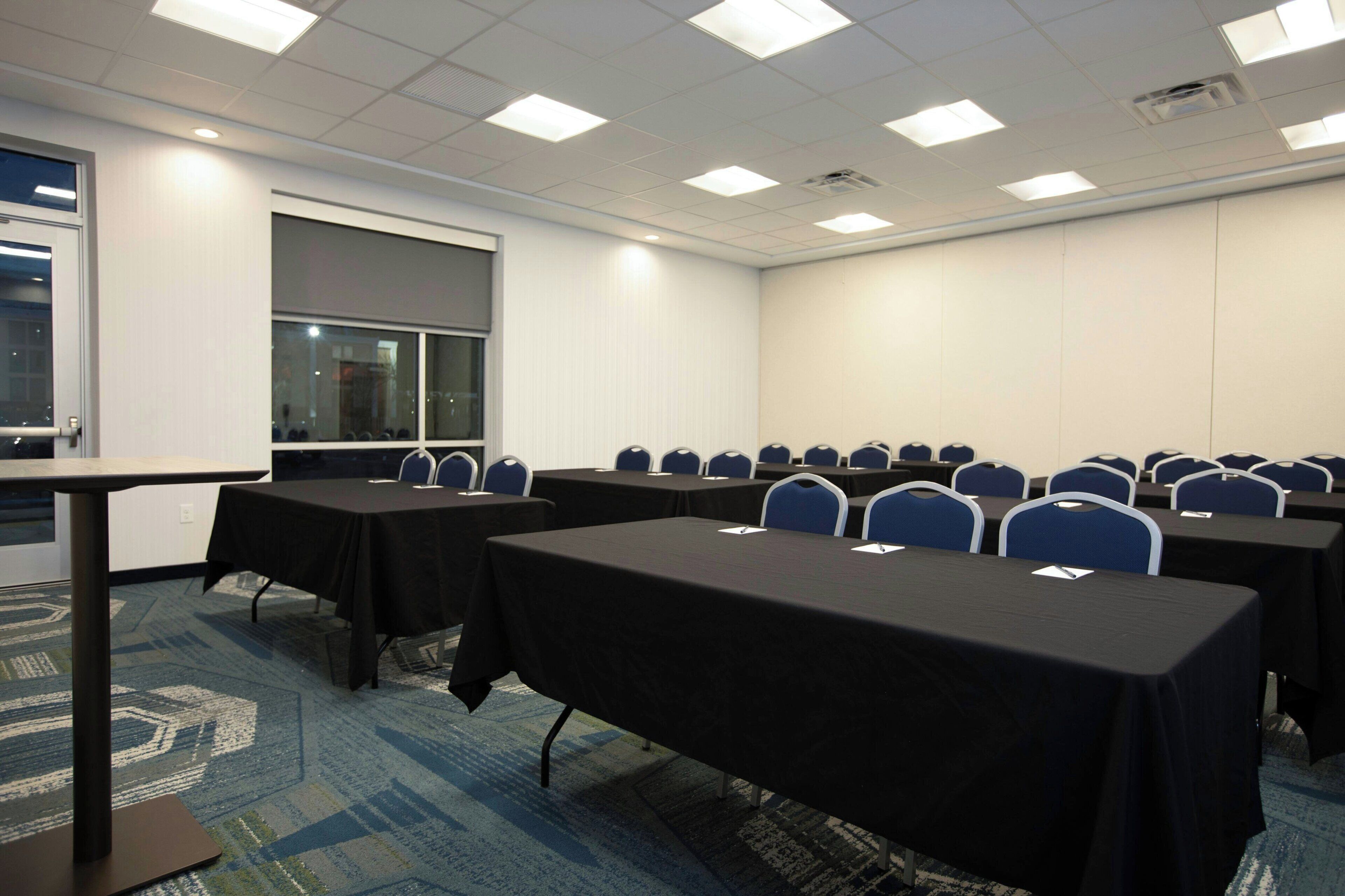 A conference room with tables, chairs, and a large window.