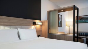A hotel room with a large bed, a bedside table, a mirror, and a wall-mounted light fixture. - Springhill Suites By Marriott Richmond Airport (Sandston)