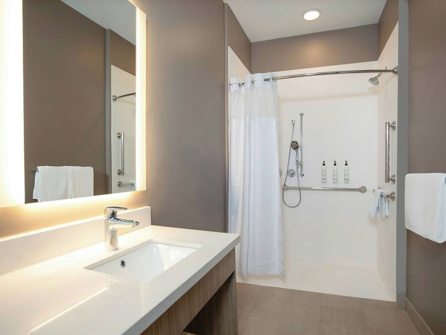 A modern bathroom with a double sink, a shower with a glass door, and a large mirror.