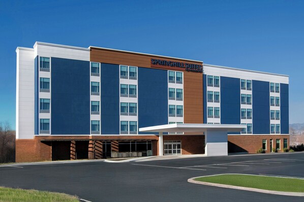 Un hotel moderno con un cartello che recita 'SpringHill Suites & Marriott'. Presenta un edificio a più piani con tetto piatto, ampie finestre e un parcheggio antistante.