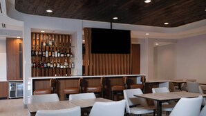 A modern hotel lobby with a bar area, seating arrangements, and a television screen. - Springhill Suites By Marriott Richmond Airport (Sandston)