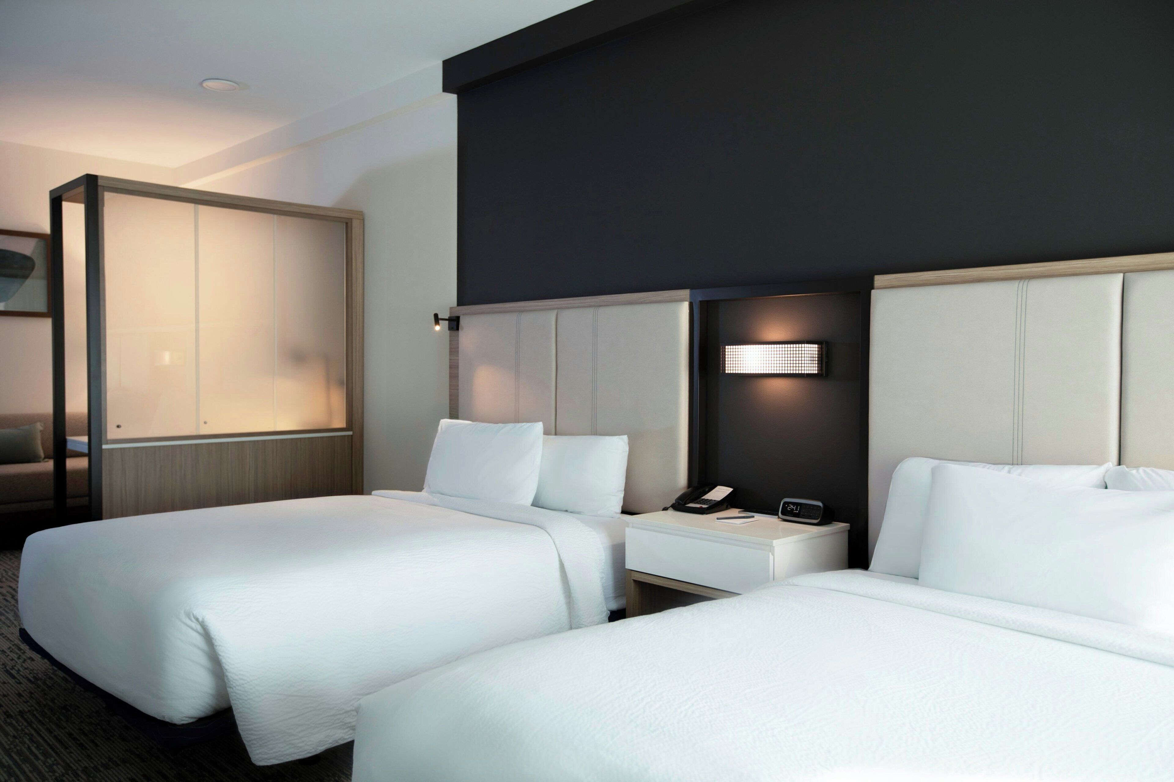 Une chambre d’hôtel avec deux lits, un bureau, un téléphone et une lampe fixée au mur.
