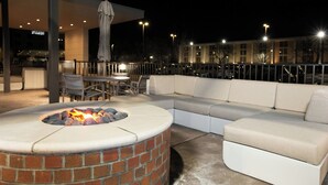 An outdoor seating area with a fire pit, a sofa, and a table with chairs. - Springhill Suites By Marriott Richmond Airport (Sandston)