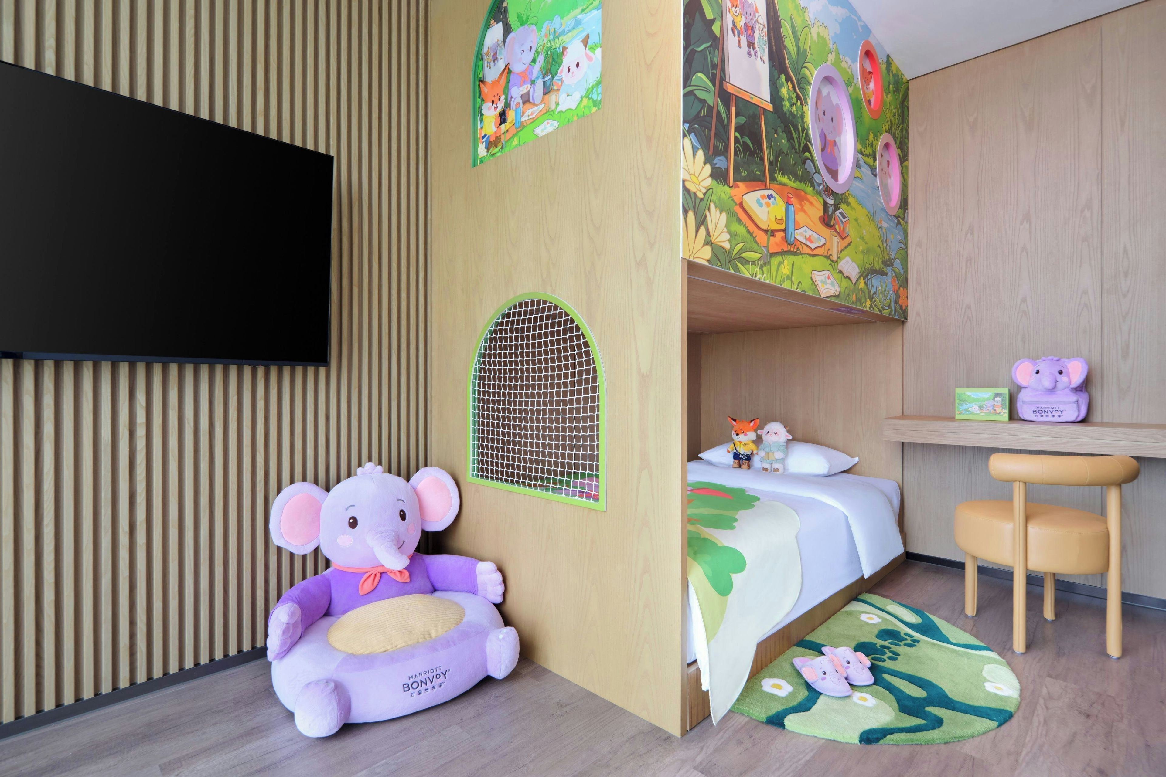 A child's room with a bed, desk, and a large TV.