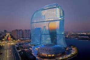 Un hôtel moderne doté d’une architecture remarquable, caractérisée par une structure en forme de dôme et une grande façade vitrée, et bénéficiant d’un emplacement privilégié au bord de l’eau.