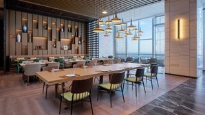 Un área de comedor moderna con mesas largas, sillas e iluminación colgante.