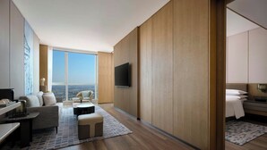 Una habitación de hotel moderna con un ventanal grande, un televisor de pantalla plana, un sofá, una mesita de café y una cama.