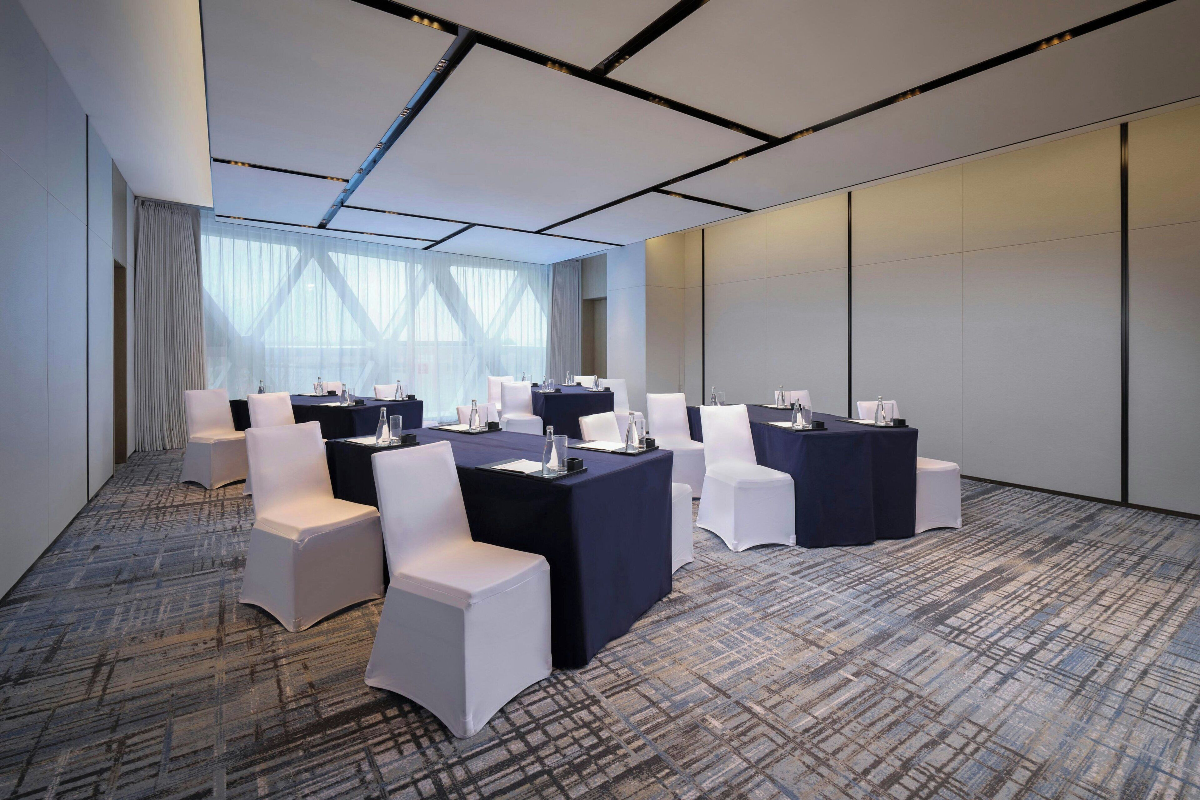 Une salle de conférence équipée de tables, de chaises et recouverte d’un tapis.