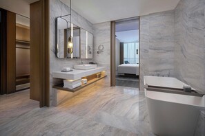 Un baño moderno con una bañera grande, dos lavamanos y un espejo.