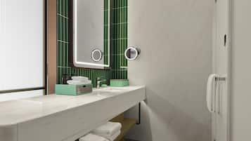A modern bathroom with a white sink, green-tiled wall, and a mirror with built-in lights.