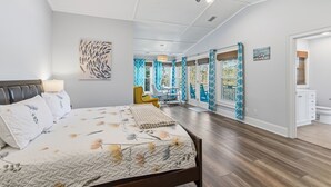 Un'ampia camera da letto con un letto grande, un ventilatore a soffitto e vista sul balcone.