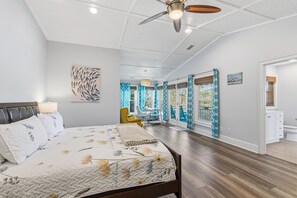 Ein geräumiges Schlafzimmer mit einem großen Bett, einem Deckenventilator und Blick auf den Balkon.