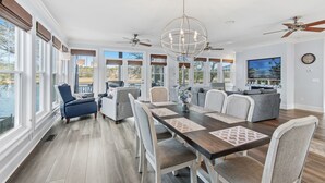 Un'ampia sala da pranzo con un tavolo in legno scuro, sedie rivestite di grigio e un lampadario.