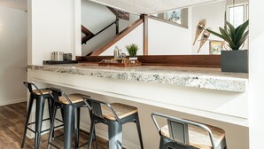 Cozinha com bancada de granito, banquetas de madeira e um vaso com planta.