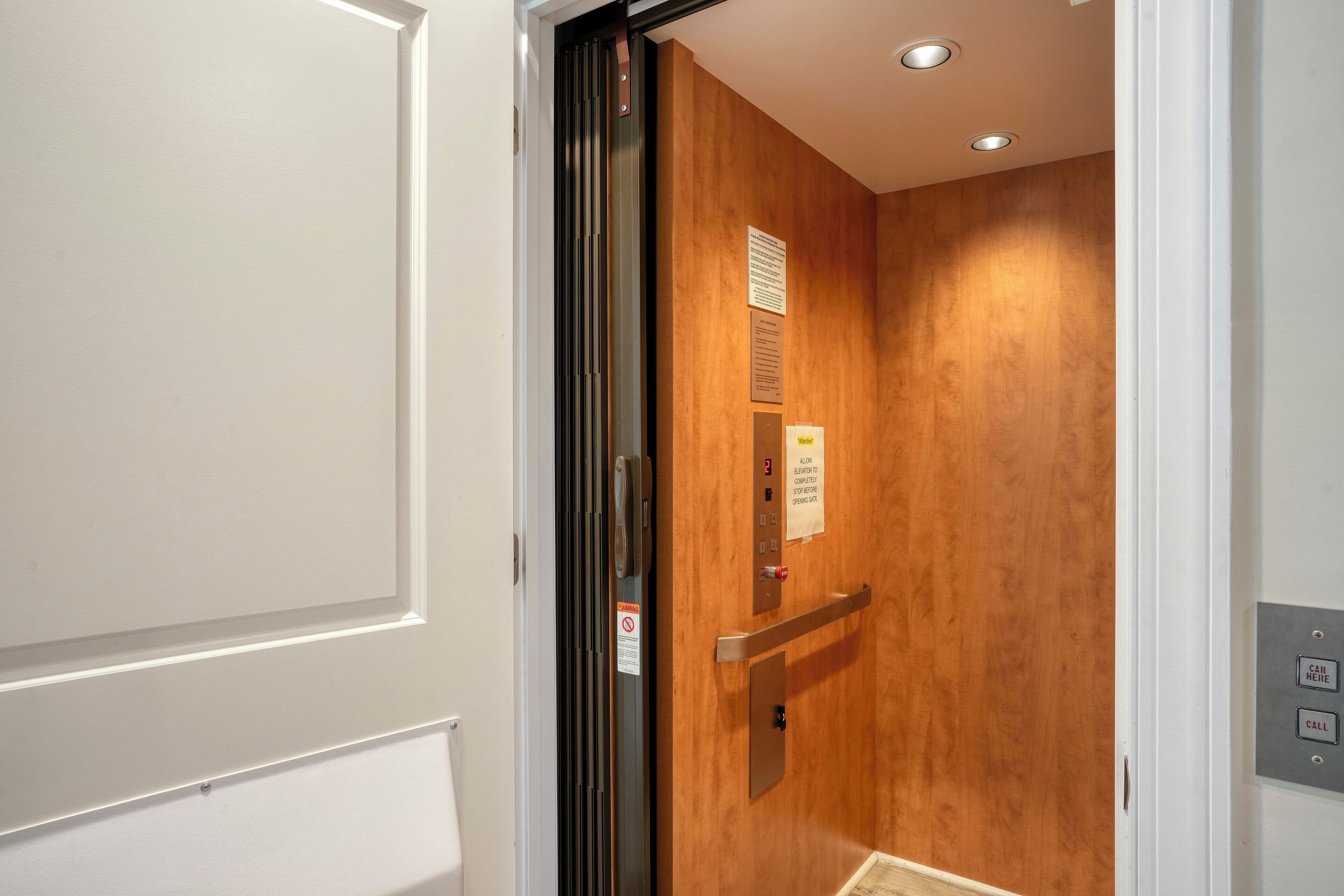 An elevator with a wooden interior and a metal handrail.
