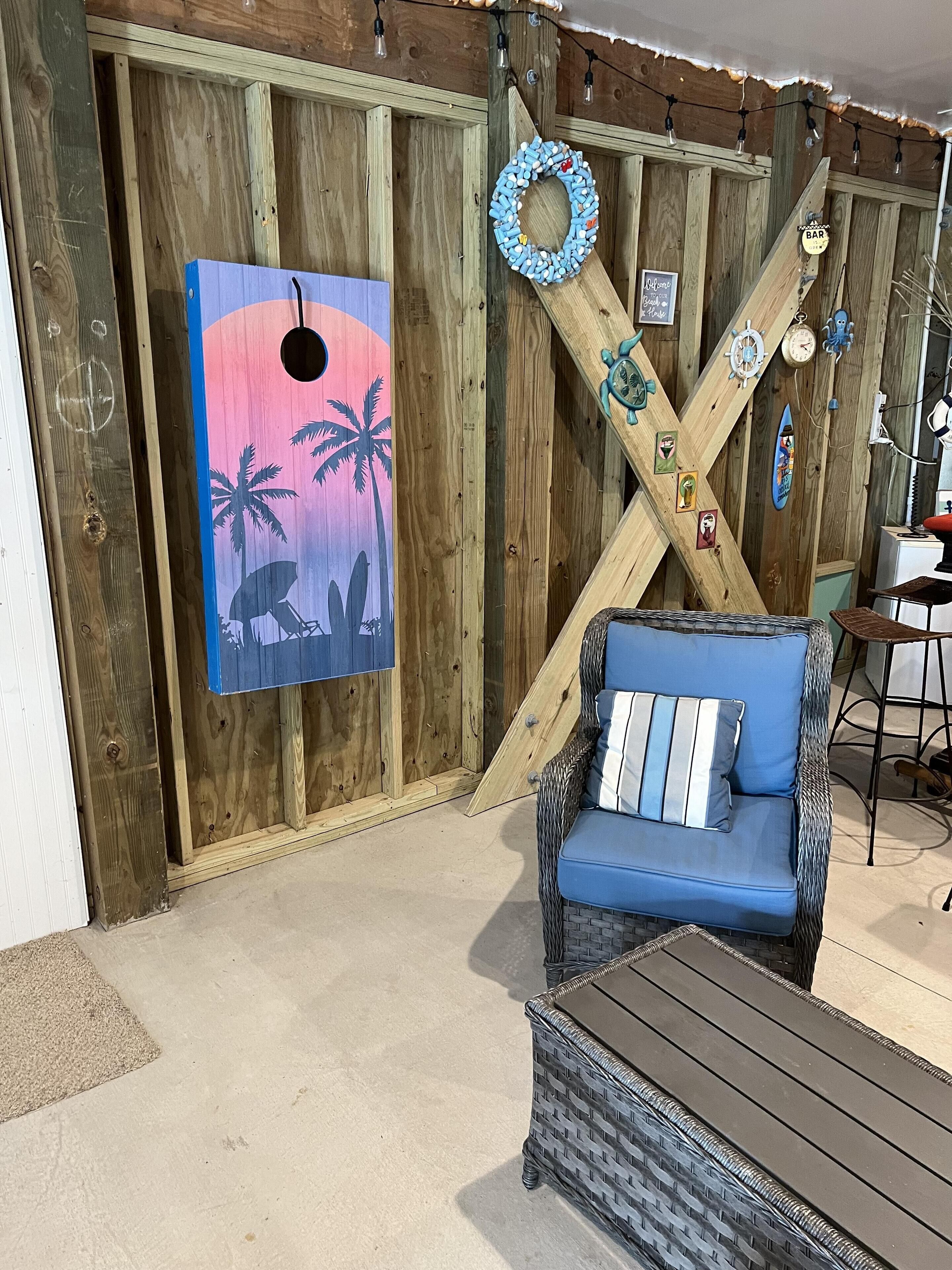 A wooden room with a blue sofa, a wooden X-shaped wall decoration, and a beach-themed painting.
