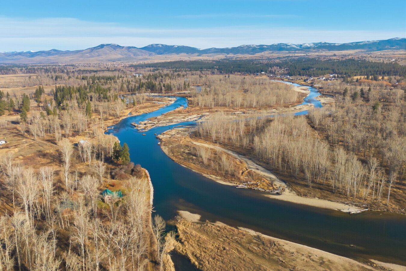 A river winding through a forested valley with mountains in the background.