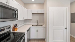 A modern kitchen with white cabinets, a stainless steel sink, and a built-in oven. - Glendale 1BR/1BA 3 Beds Pool, Gym & Parking (Glendale)