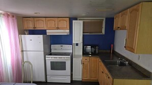 Una cocina compacta con refrigerador, estufa, microondas y armarios de madera.