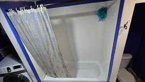 Un baño con bañera, inodoro, lavadora y lavamanos.
