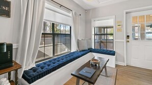 Une pièce avec un banc intégré doté de coussins bleus, une machine à café et une table sur laquelle se trouvent un carnet et un stylo.