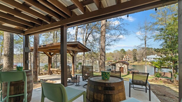 Un espace extérieur aménagé en terrasse, avec des tables et des chaises en bois, un tonneau en bois et une pergola.