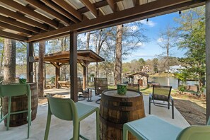 Un espace extérieur aménagé en terrasse, avec des tables et des chaises en bois, un tonneau en bois et une pergola.