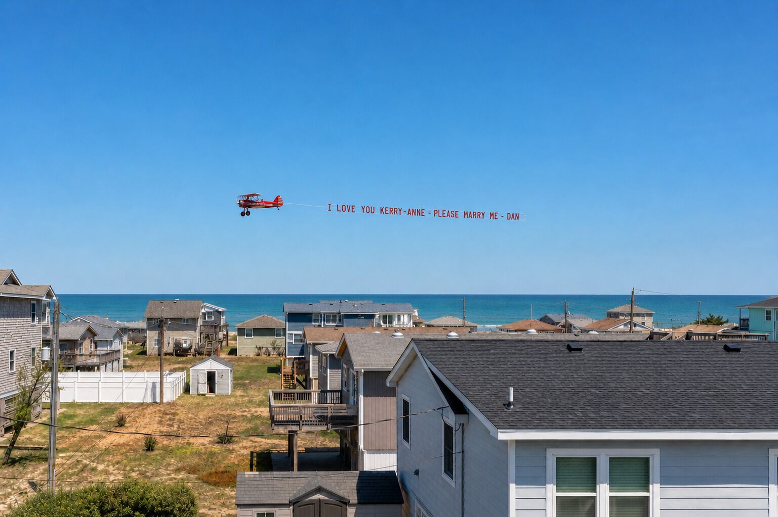 A residential area with houses, a beach, and a red biplane with a message in the sky.