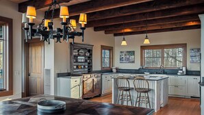 Una cocina amplia con una isla grande, vigas de madera e iluminación colgante.