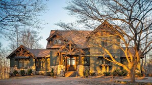 Una casa grande de estilo rústico con un porche delantero destacado y cimientos de piedra.