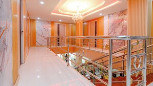 A modern hotel interior with a marble floor, a staircase with metal railings, and a chandelier. - PSA Palace Khaosan (Bangkok)