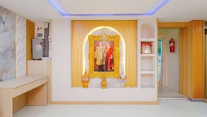 A room with a wooden desk, a framed picture, and a shelf with a fire extinguisher. - PSA Palace Khaosan (Bangkok)